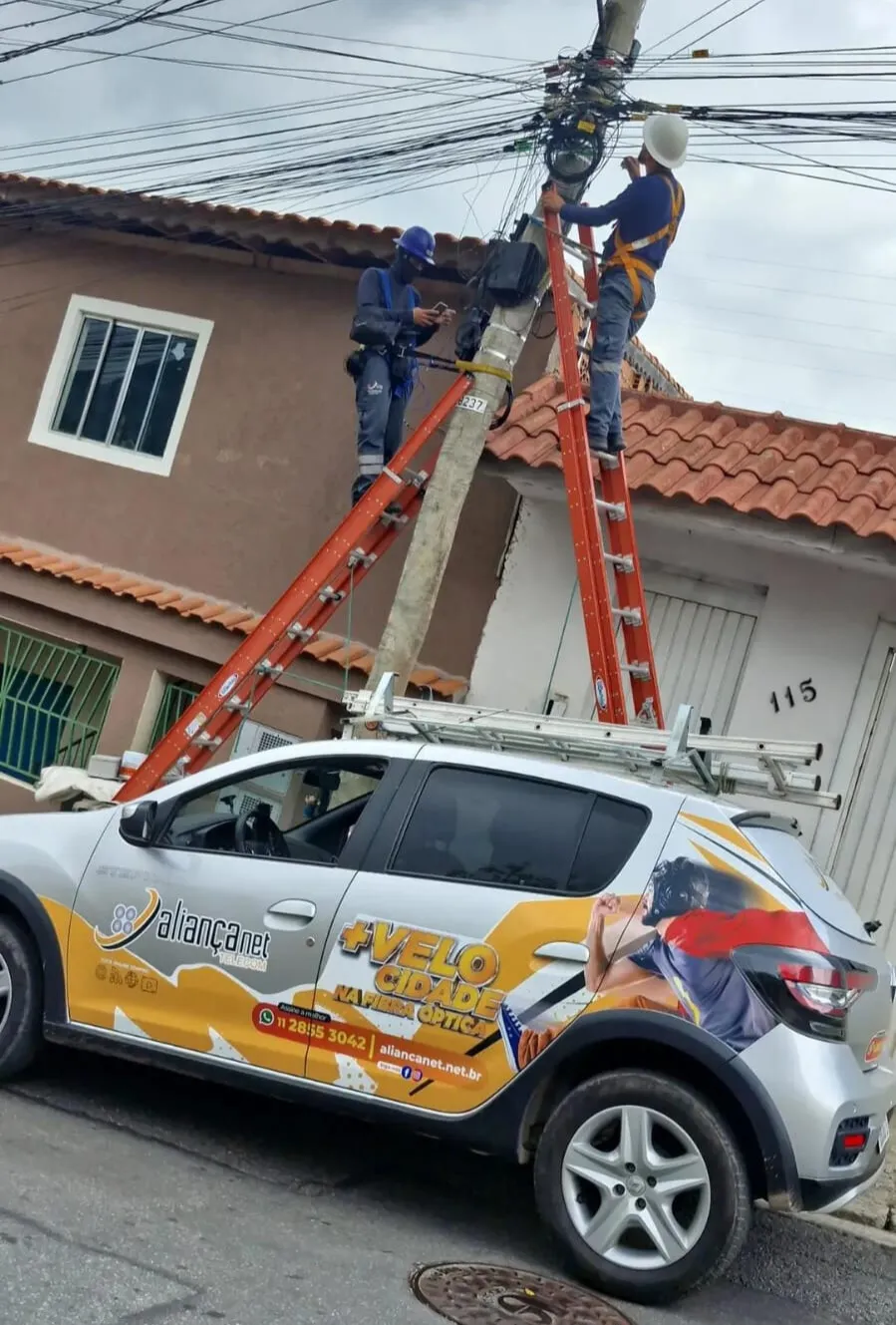 Técnicos próprios da Aliança Net instalando a fibra óptica no poste
